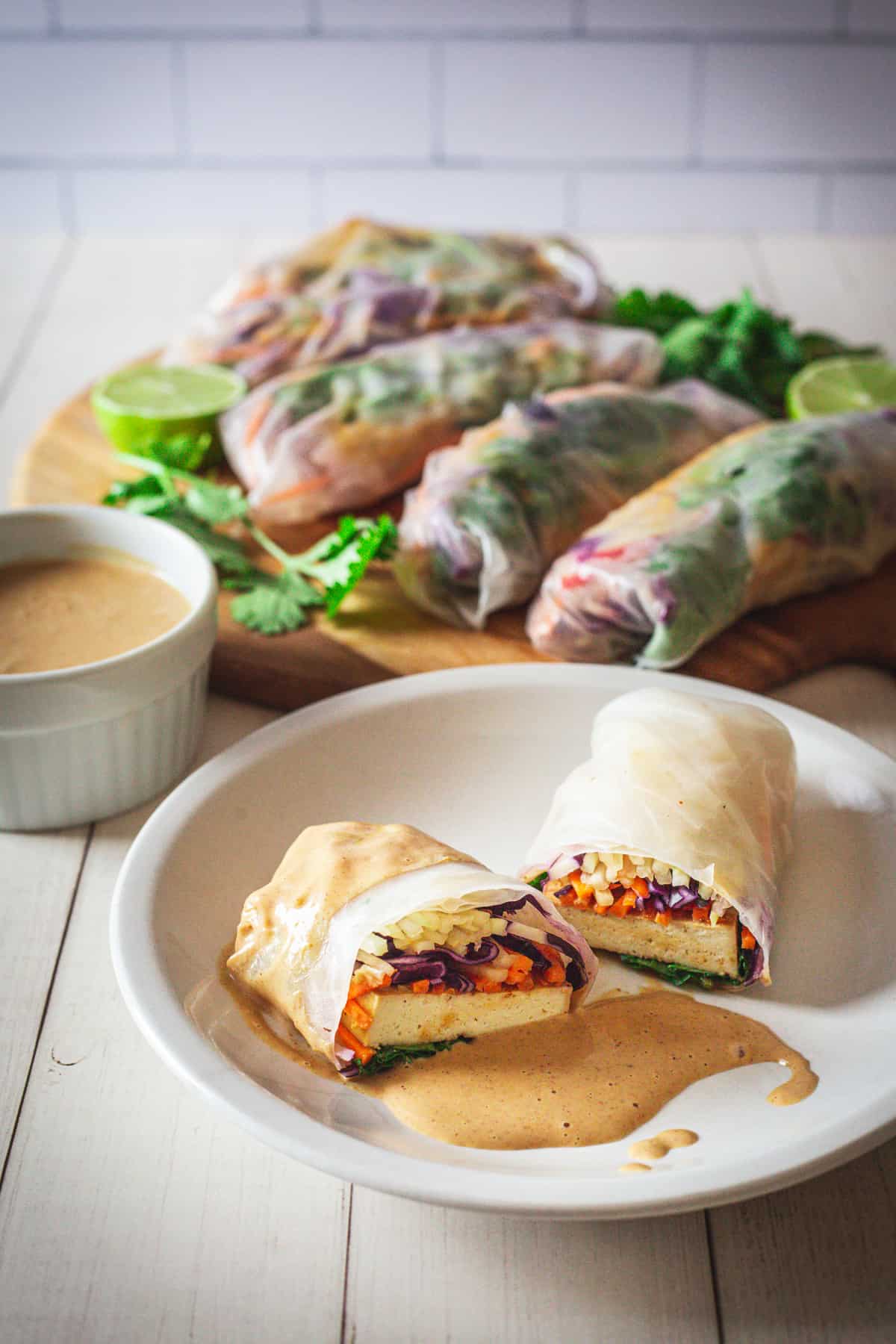 a spring roll on a plate with tofu spring rolls on platter and dipping sauce