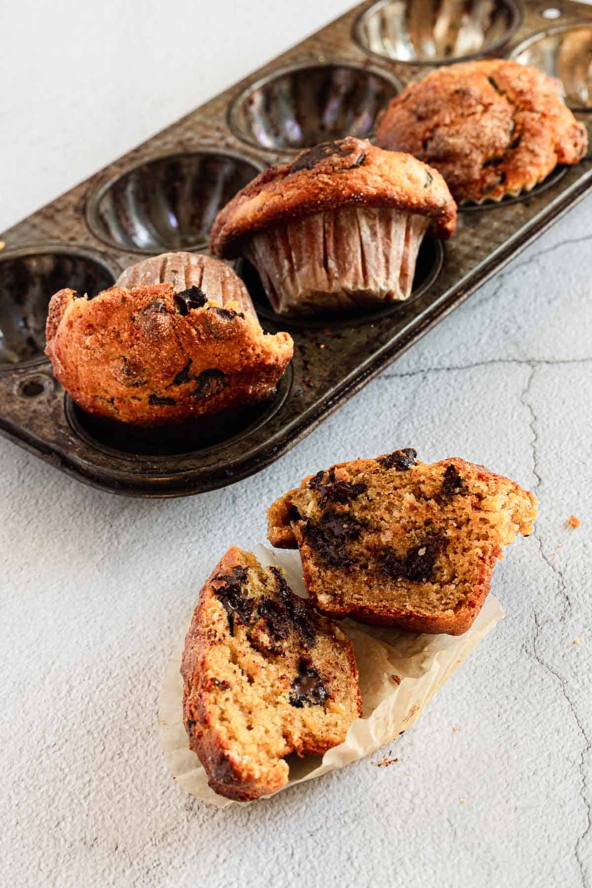 close up on gluten free chocolate chip muffin halves with muffins in background