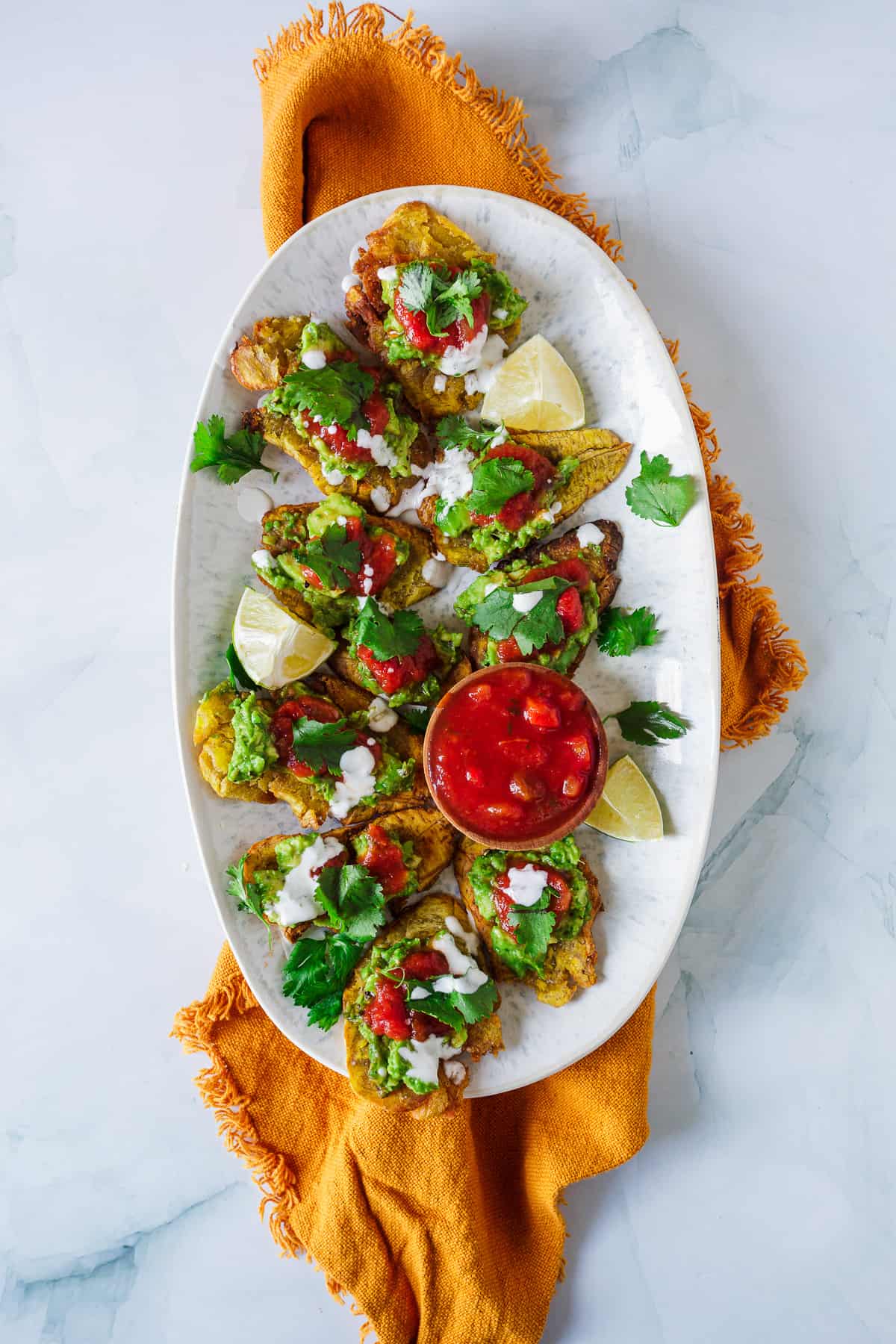 A traditional platter of tacos with guacamole, lime, cilantro, and a side of salsa.