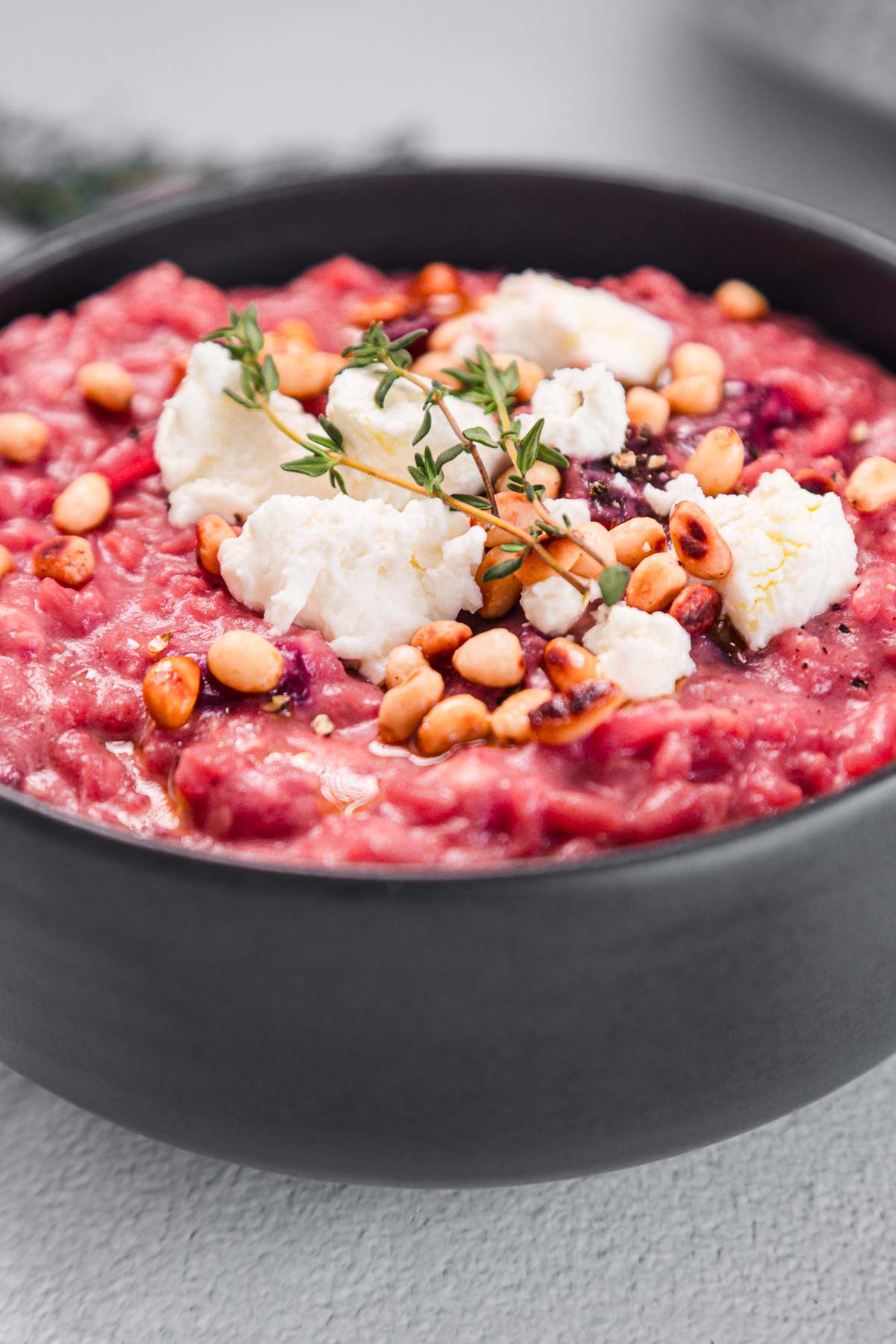 A bowl of red rice with cheese and herbs.